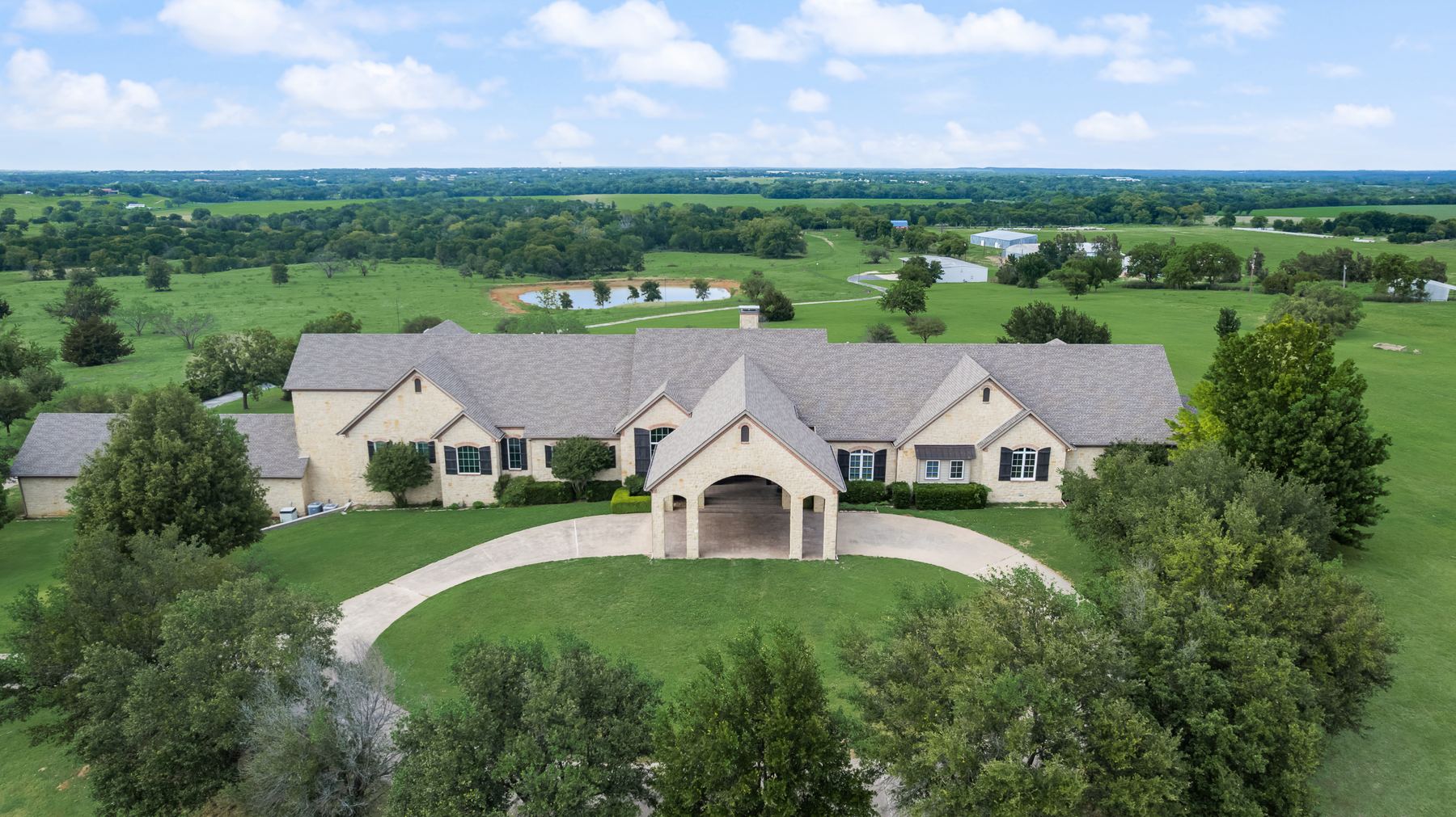 Aerial view of the limestone ranch estate surrounded by pasture and a private pond